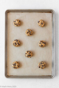 Scooped oatmeal raisin chocolate chip cookies on a prepared baking sheet before going into the oven.
