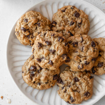 An overhead shot of a white plate of oatmeal raisin chocolate chip cookies.
