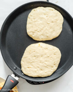 Fluffy buttermilk pancakes cooking on a griddle.