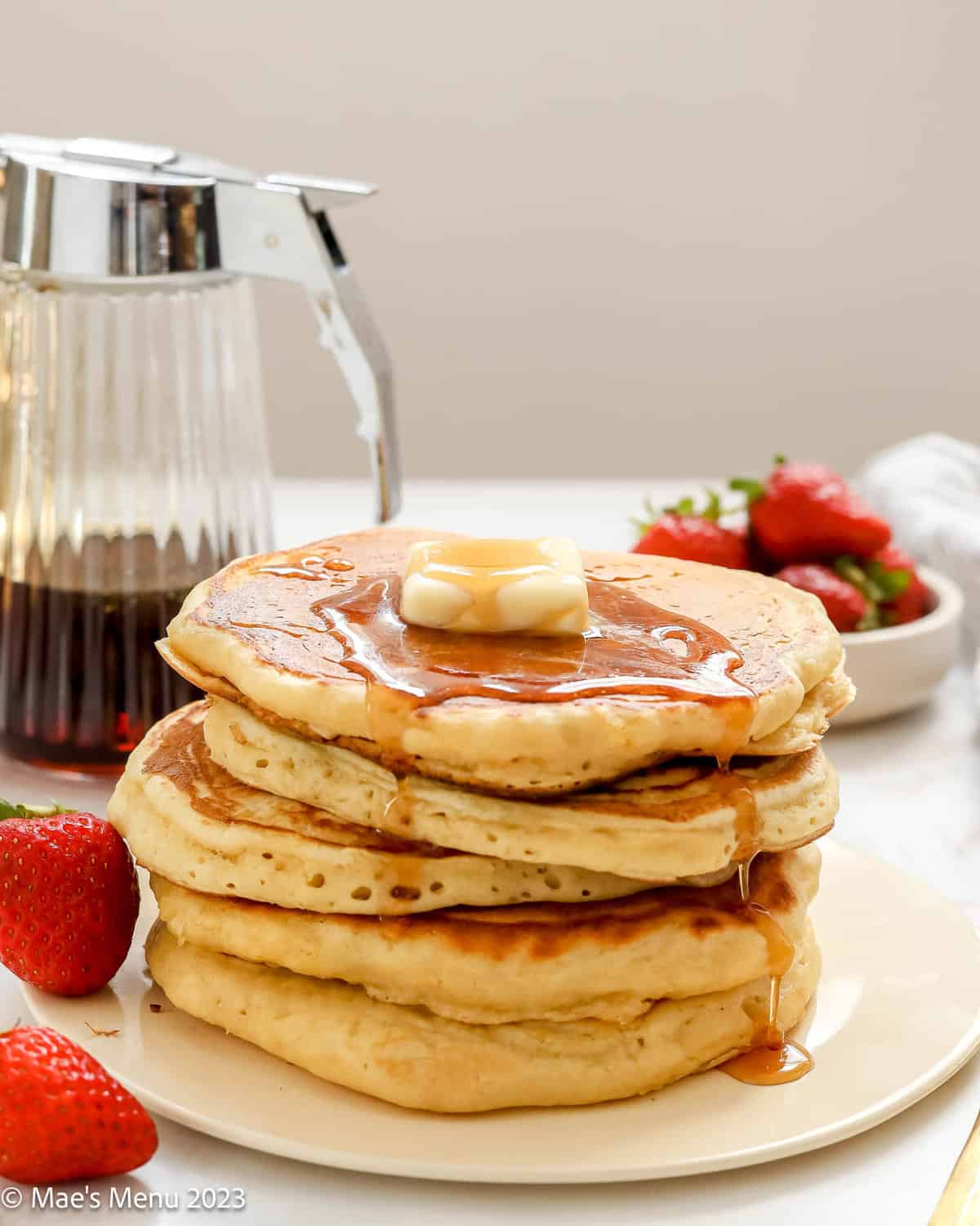 A stack of fluffy buttermilk pancakes drizzled with maple syrup.