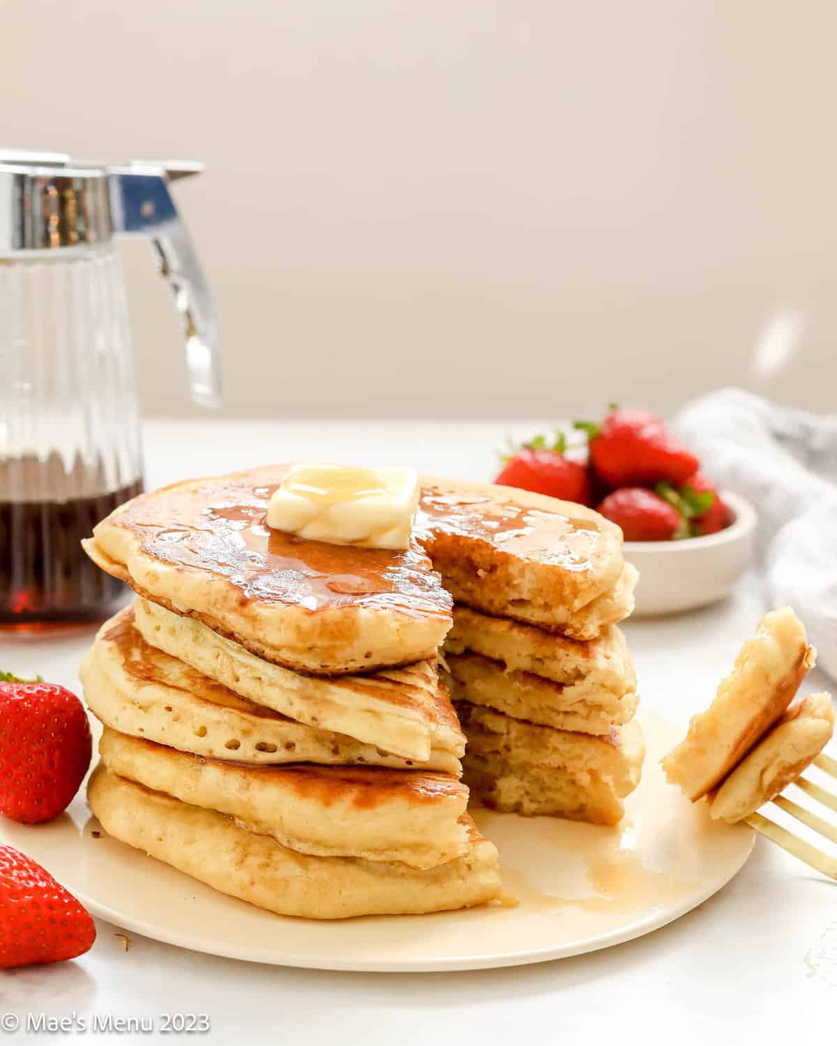A stack of fluffy buttermilk pancakes with a bite taken out of them.