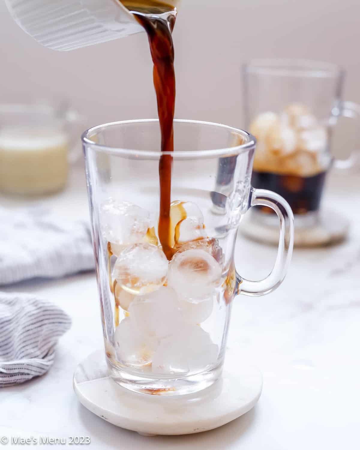 Pouring a shot of espresso into a glass of ice.