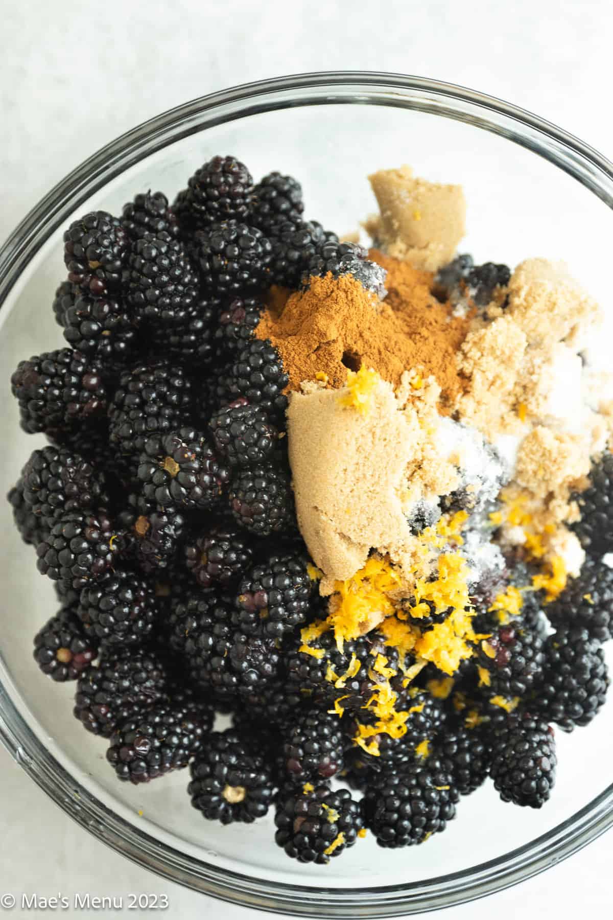 A mixing bowl of blackberries, brown sugar, lemon zest, and cinnamon.