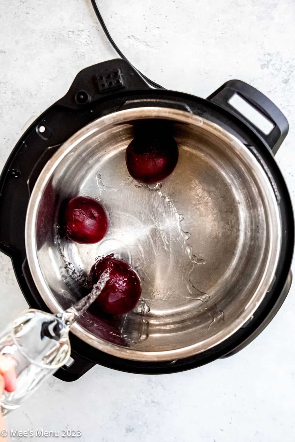 Pouring water into the instant pot with the beets.