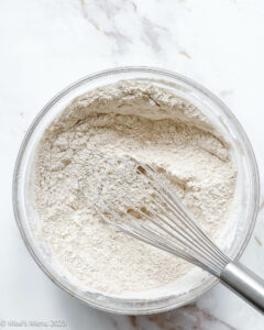 Whisked flour with a whisk in a glass bowl.