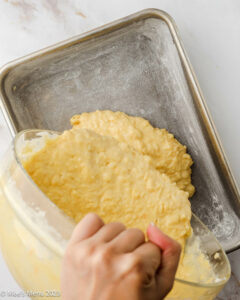 Pouring the pineapple poke cake better into the prepared baking pan.
