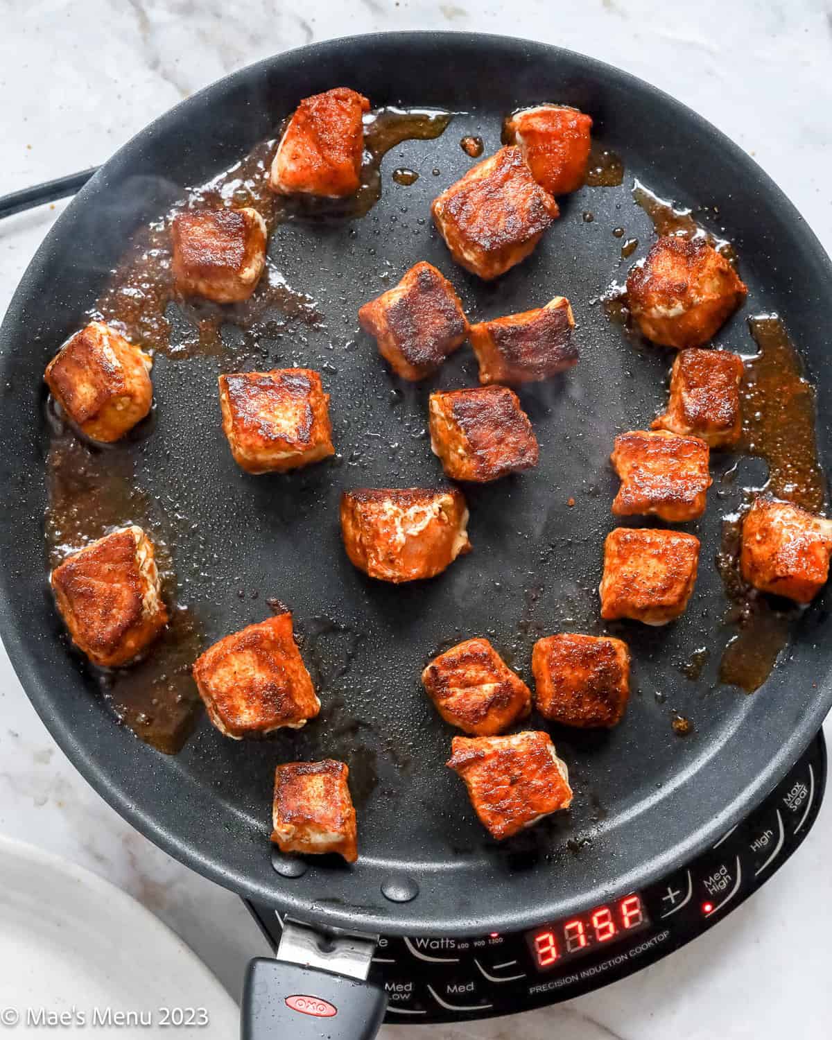 Cooking the seasoned pork chop cubes on a griddle.