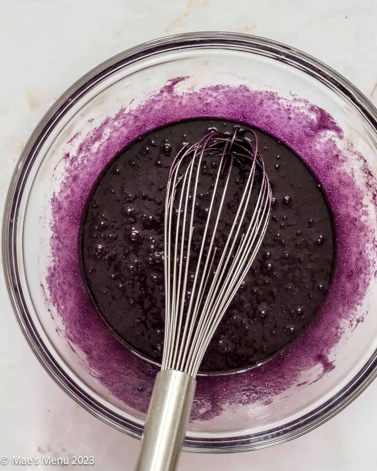 A glass mixing bowl of the wet ube brownie ingredients.