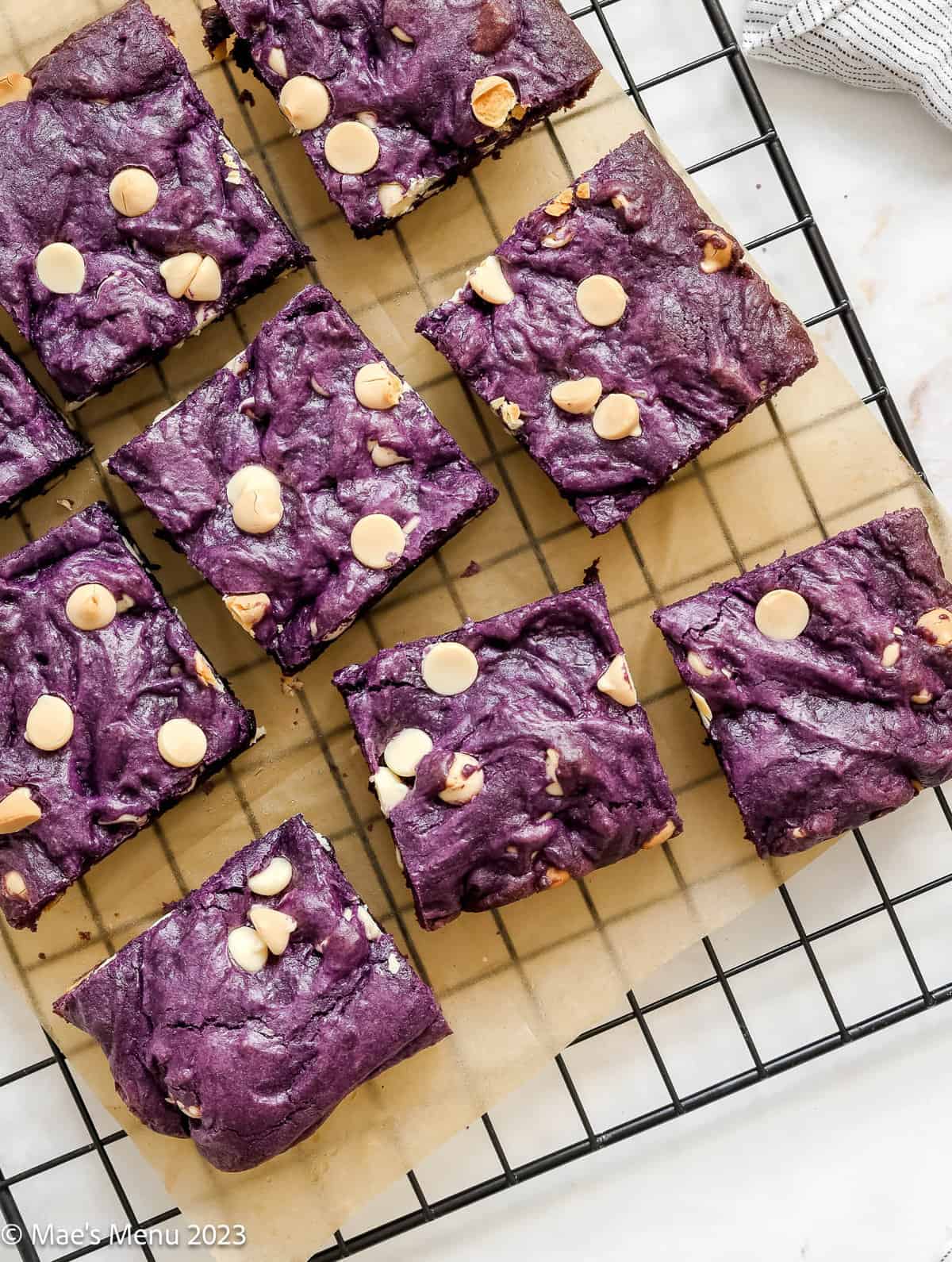 An overhead shot of ube brownies cooling on a parchment paper lined cooling rack.