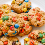 A pinterest pin for oatmeal M&M cookies with an overhead shot of the cookies on a white plate.