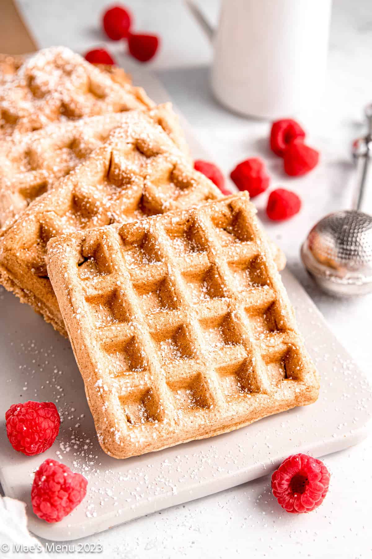 A closeup side shot of dairy-free waffles on a platter with raspberries.