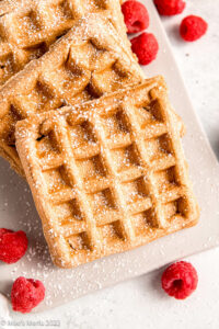 Closeup shot of dairy-free waffles on a platter with raspberries.