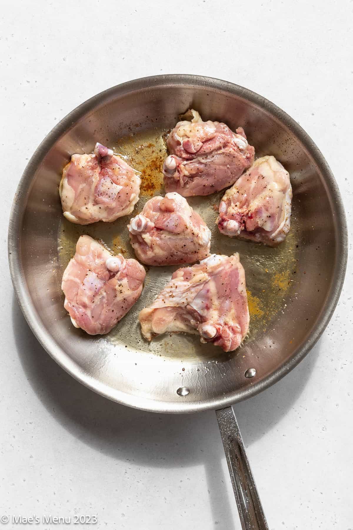 A large skillet of cooking chicken thighs.