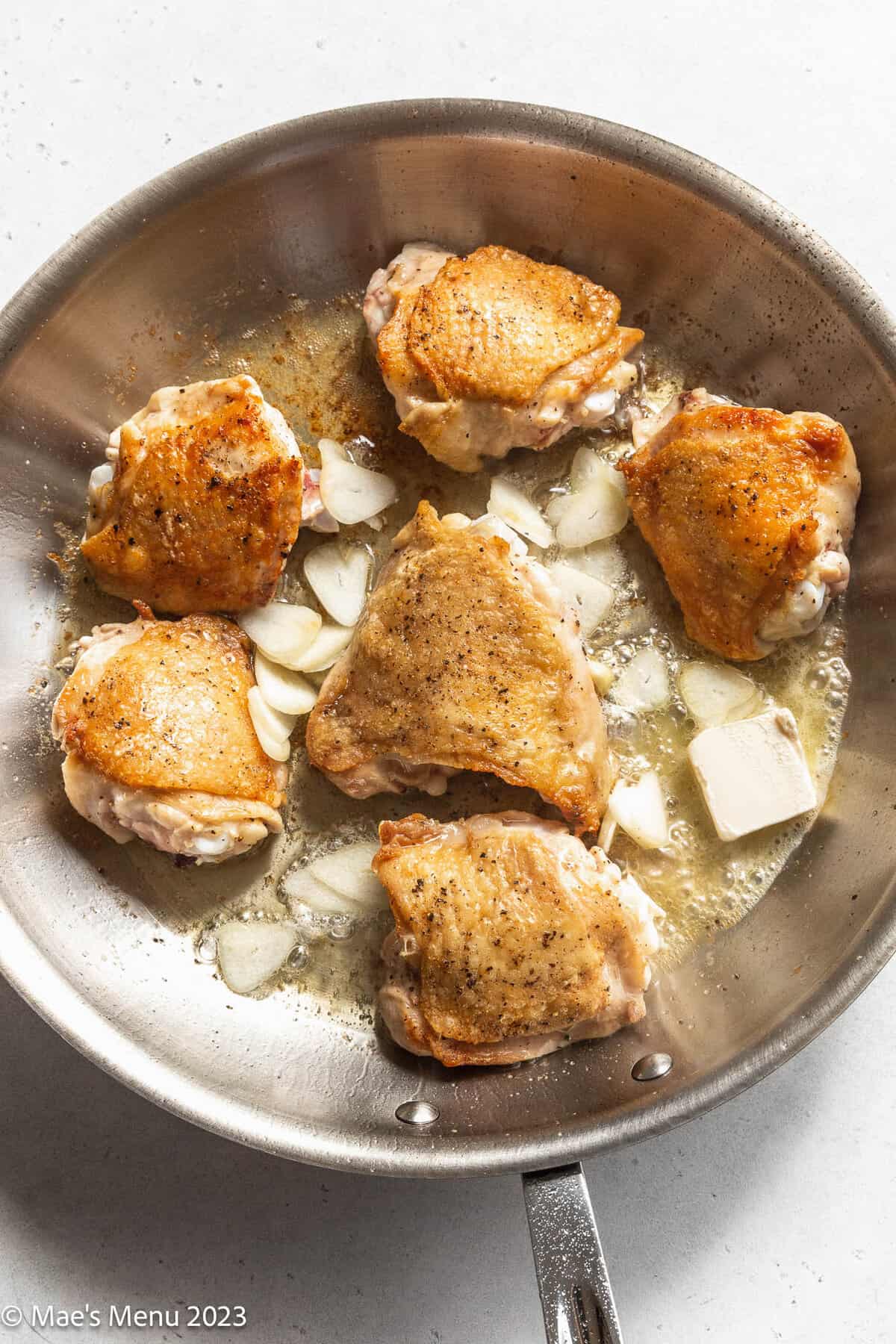 Seared chicken with garlic and butter in a skillet.