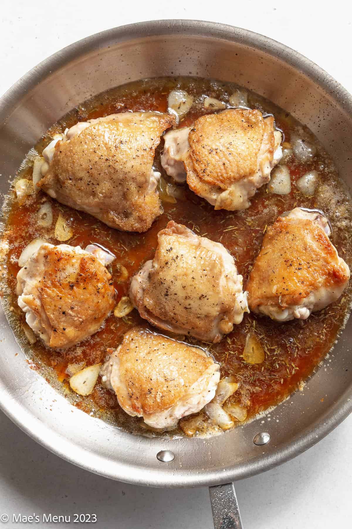 The honey garlic chicken thighs in a skillet with the sauce before roasting in the oven.