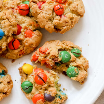 a close up of oatmeal M&M cookies, one cookie broken in half