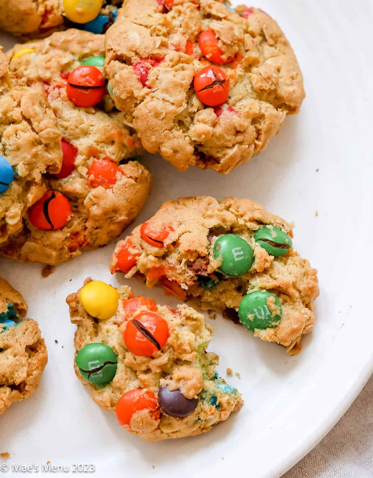 a close up of oatmeal M&M cookies, one cookie broken in half