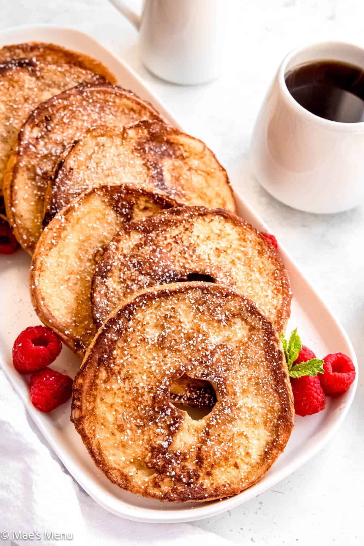 An angled shot of bagel french toast on a serving platter next to a small cup of coffee.