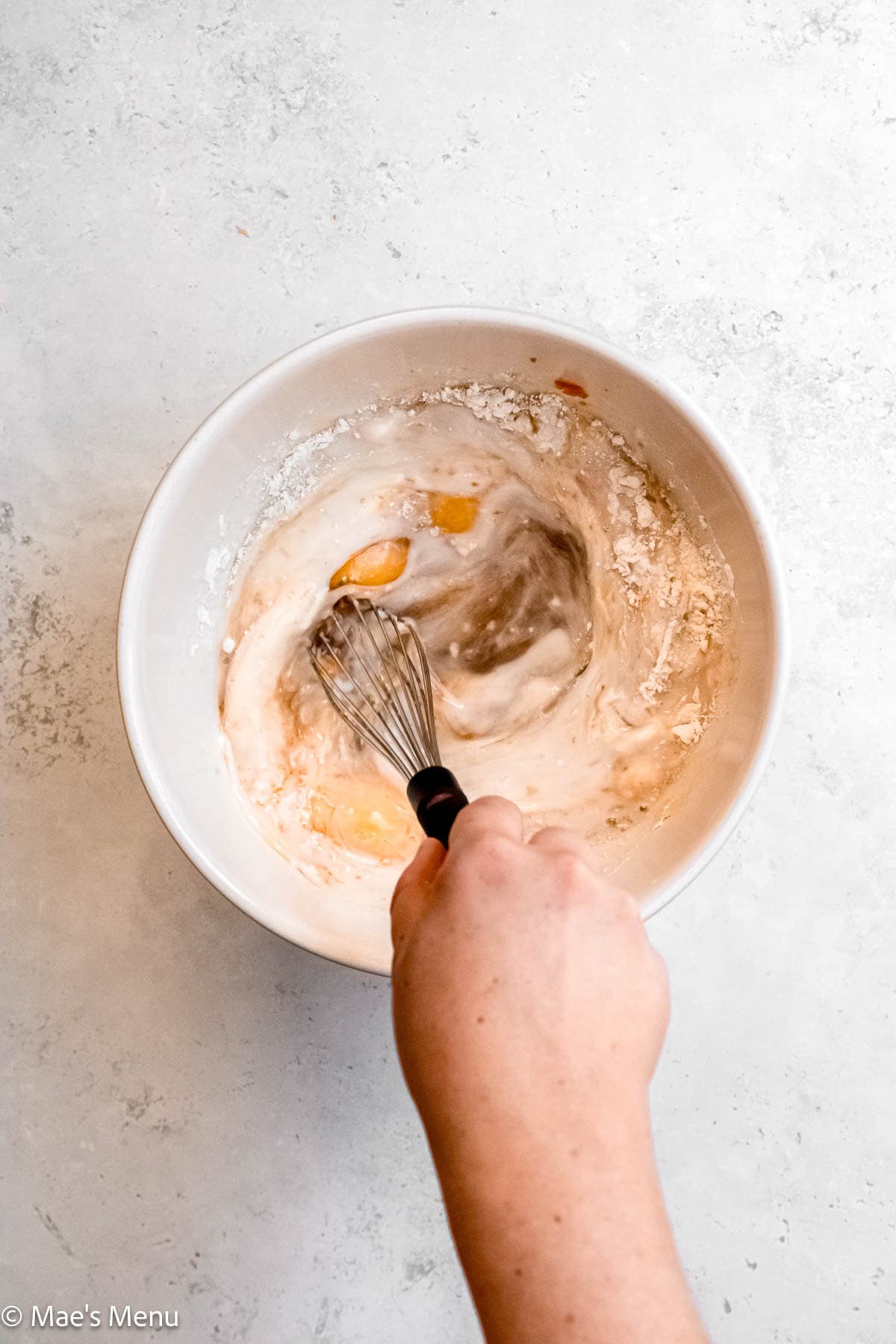 Whisking the bagel french toast together in a mixing bowl.