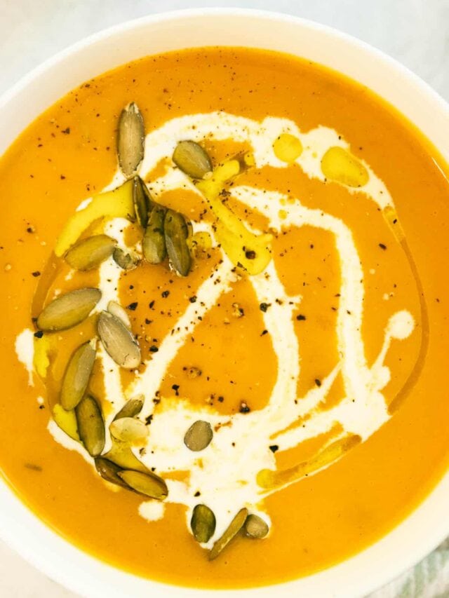 Closeup overhead shot of a bowl of vegan butternut squash soup with pumpkin seeds, olive oil, and cream.