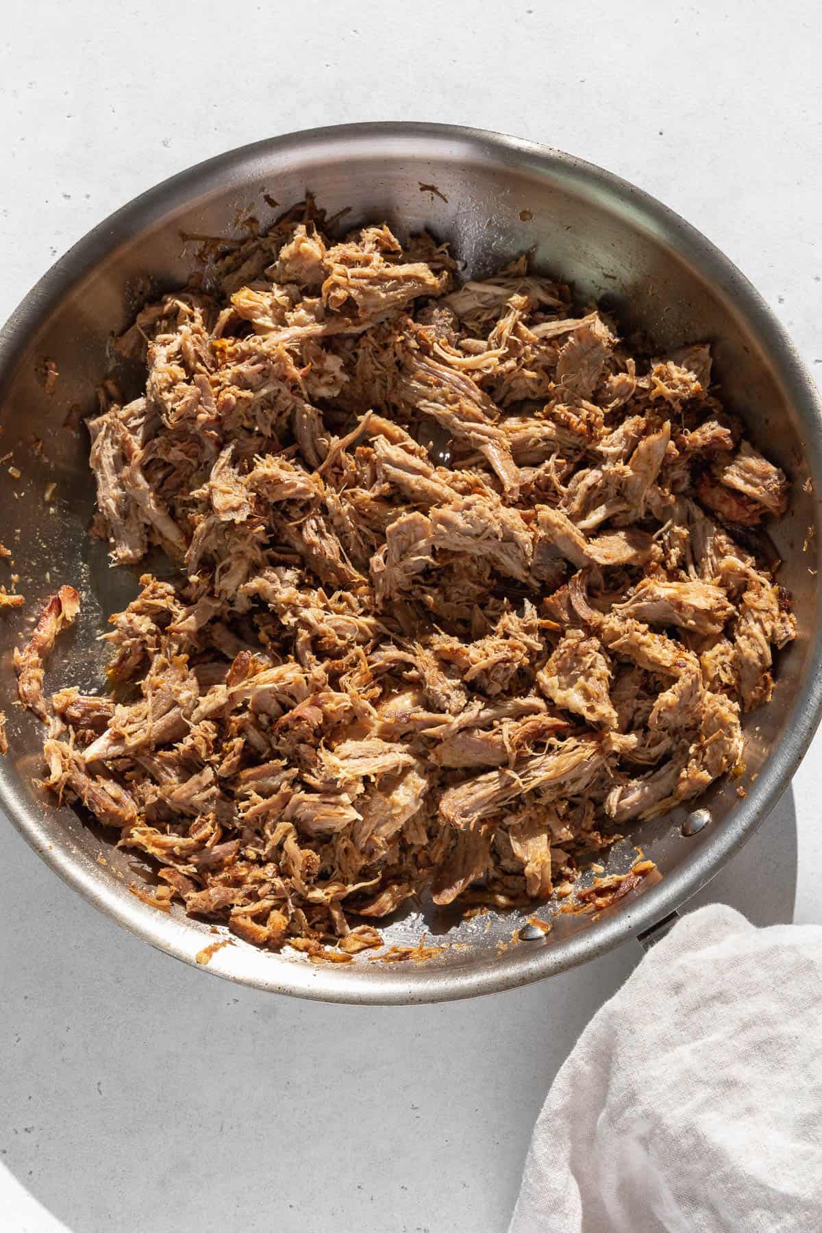 Crisped carnitas in a large skillet on the counter top. 