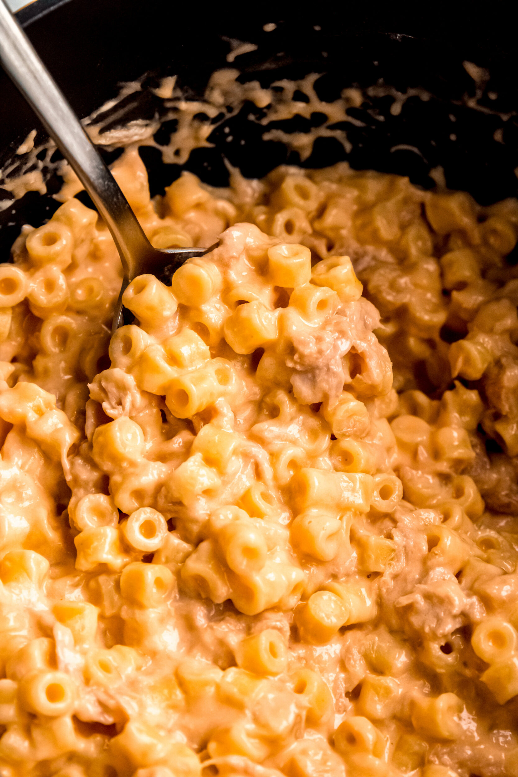 An up-close shot of stirring the tuna mac and cheese in a pot.
