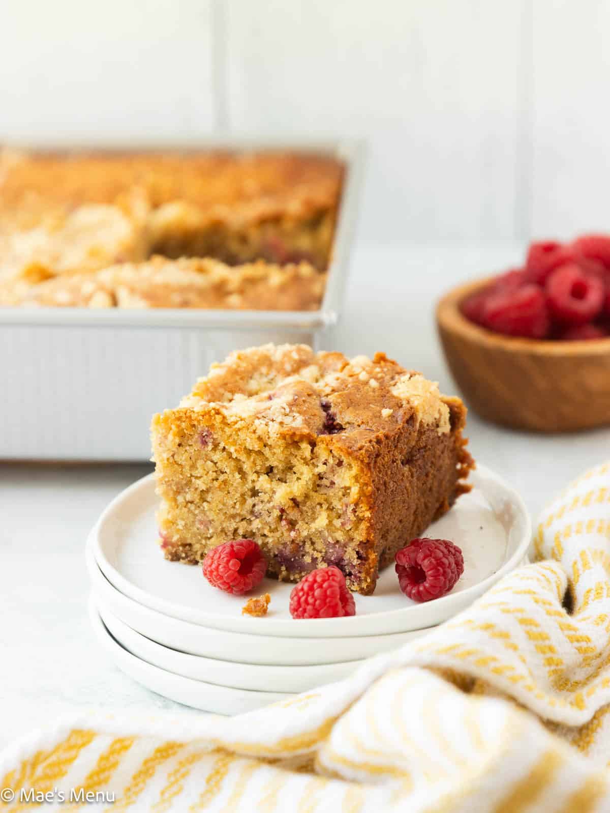 A small slice of raspberry coffee cake on a plate in front of the pan.