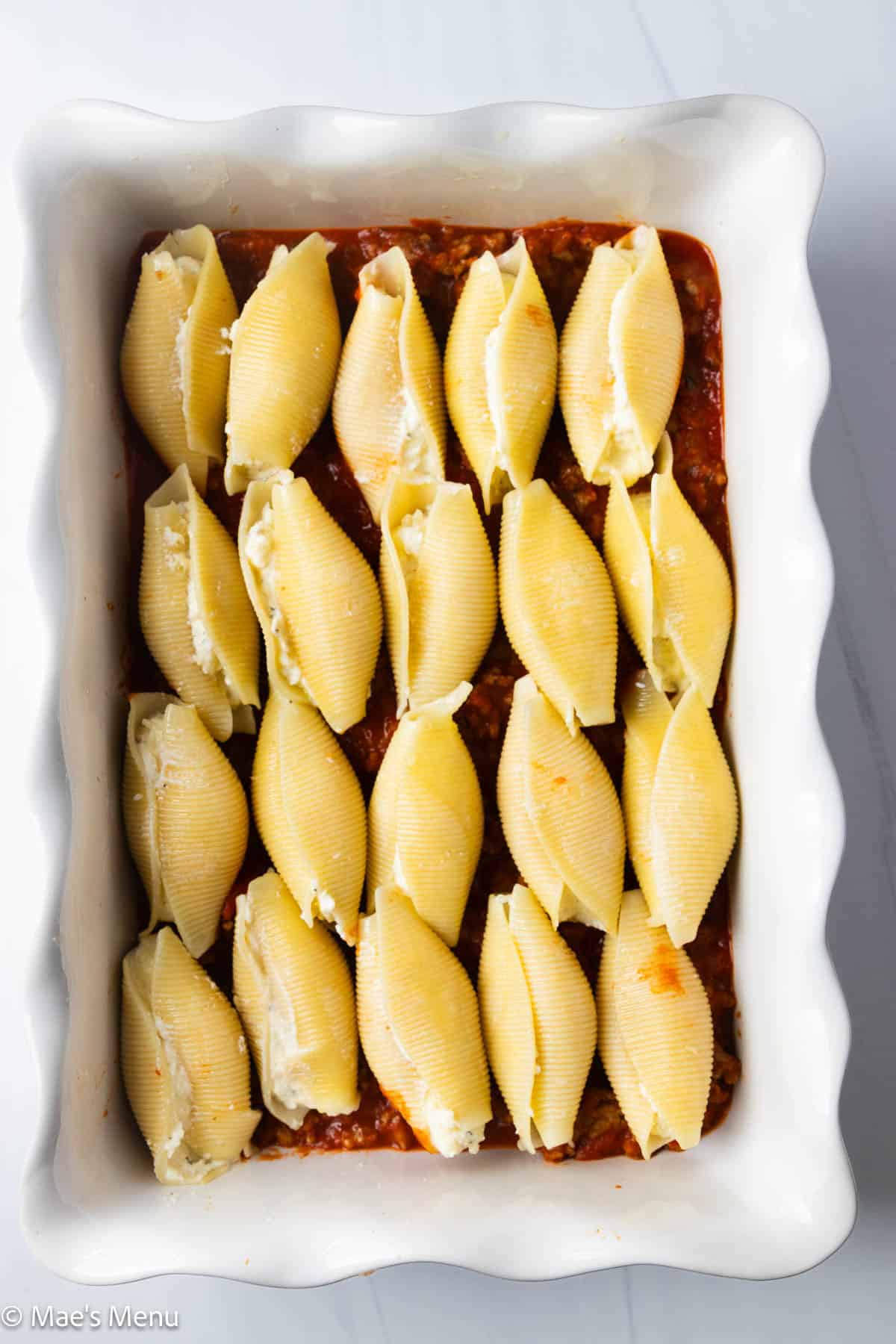 A baking pan of the stuffed shells before covering in sauce and cheese.
