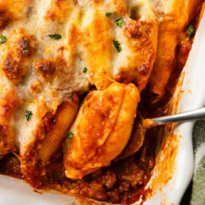 An overhead shot of a pan of baked stuffed shells with a serving spoon.