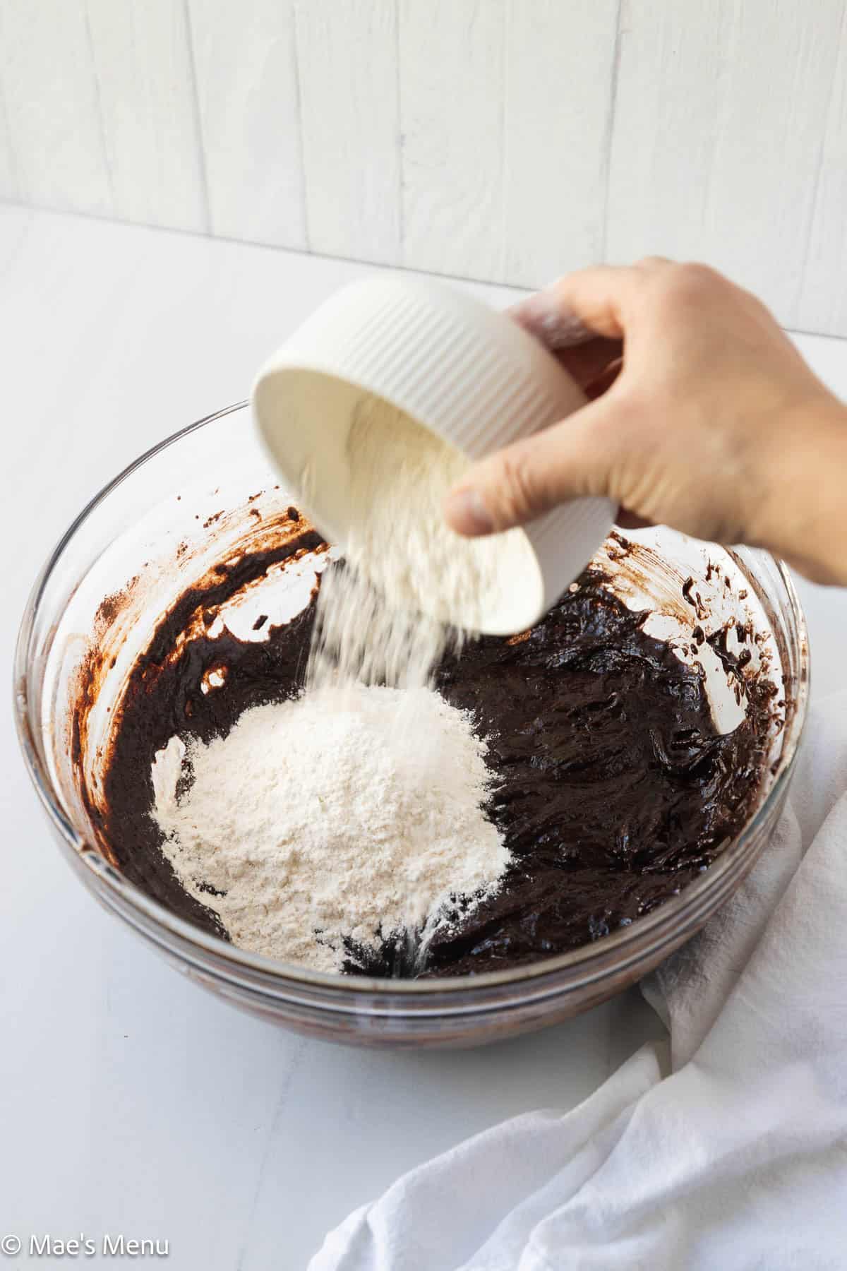 Pouring the flour into the bowl with the borwnie batter. 