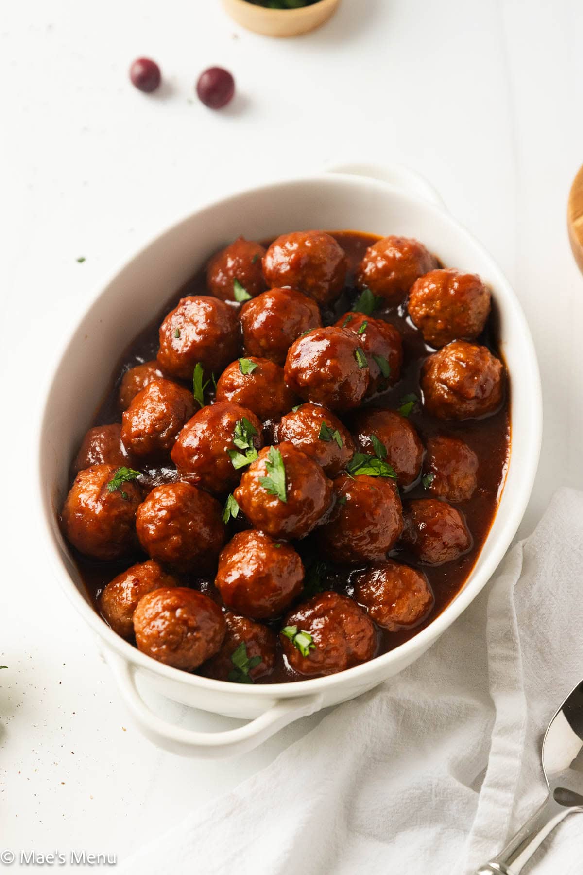 An angled overhead shot of a serving bowl of meatballs with cranberry sauce