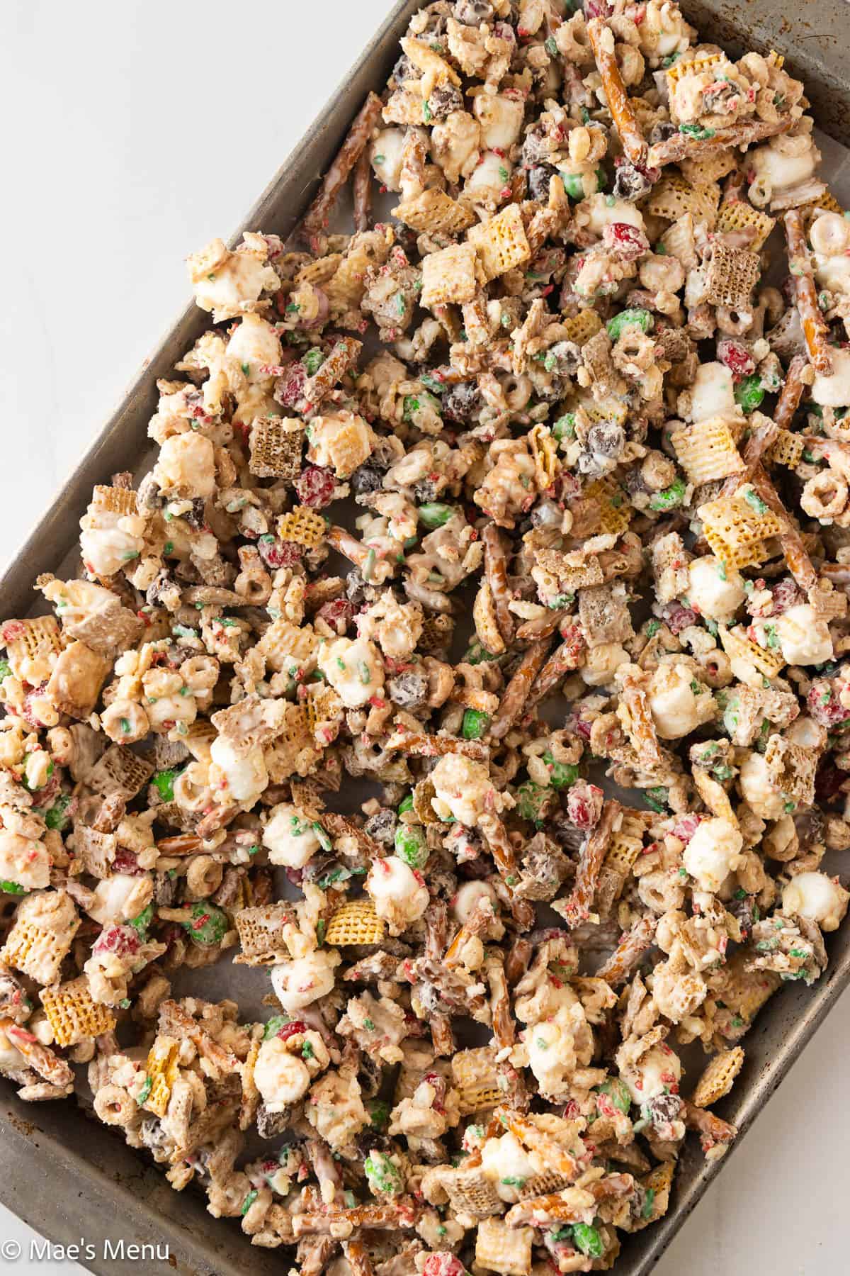 An overhead shot of a baking pan of the christmas chex mix before chilling and setting.