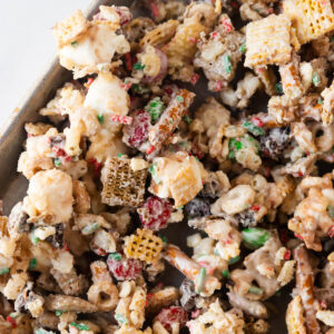 A close-up overhead shot of the Christmas chex mix on a baking sheet.