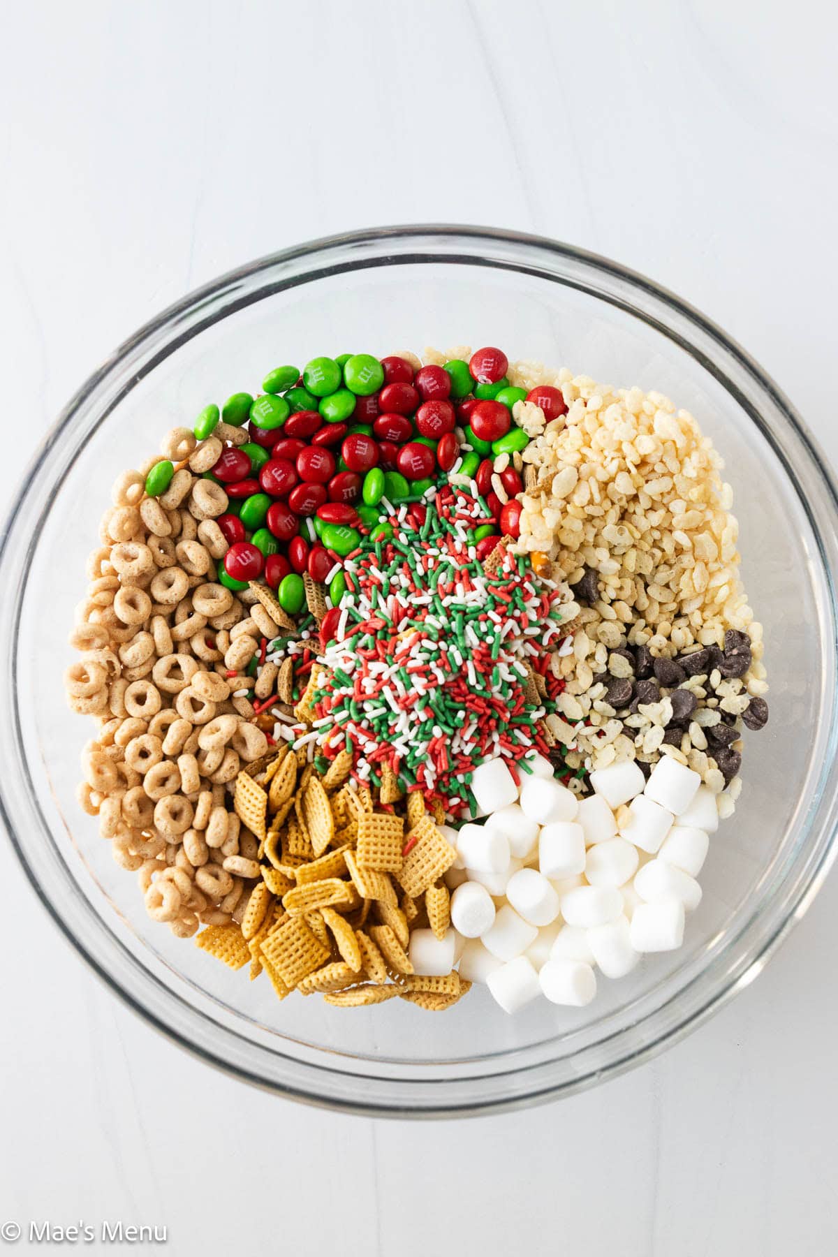 The bowl of christmas chex mix ingredients before stirring.