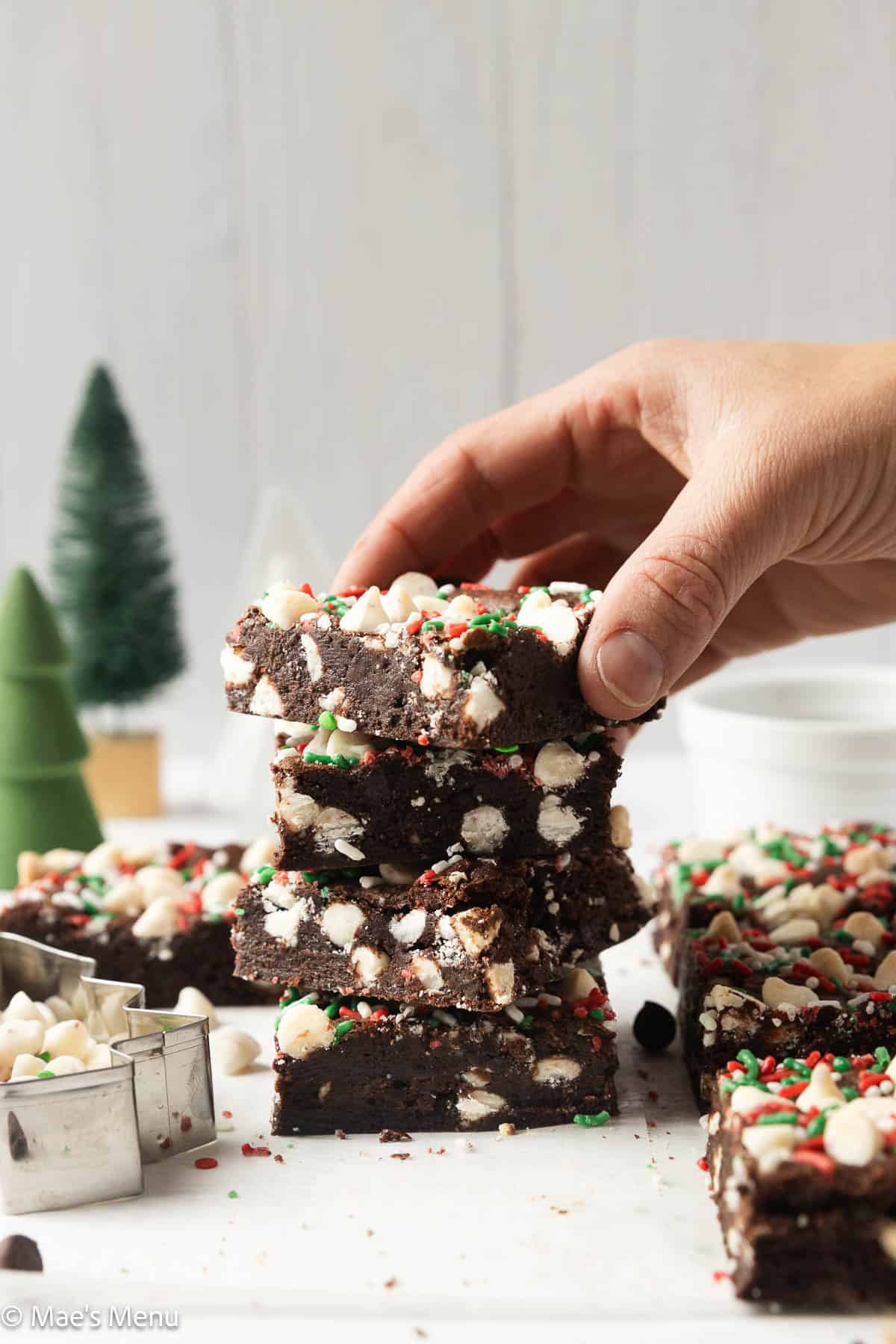 A hand taking a brownie from a tall stack on the counter.