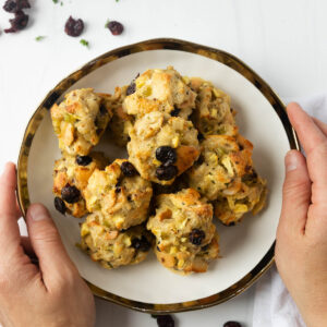 two hands serving a small plate of stuffing balls.