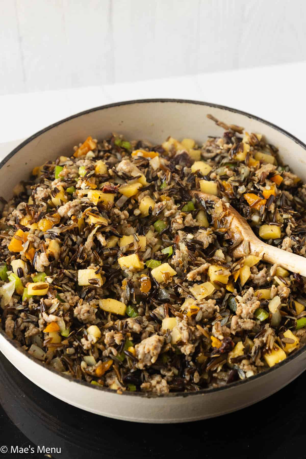 A close-up side shot of a pan of wild rice stuffing cooking on a hot pad.