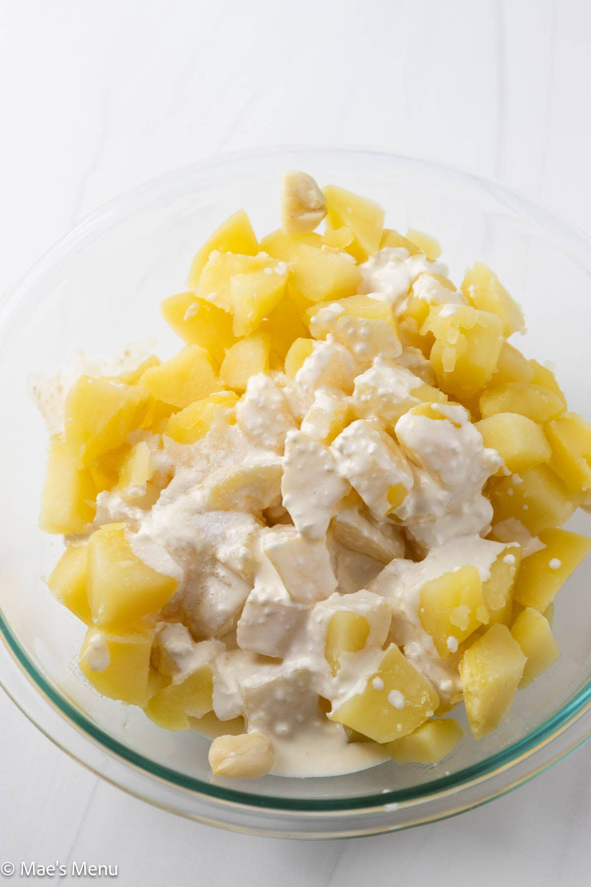 A mixing bowl with steamed potatoes and melted cream cheese mixture.