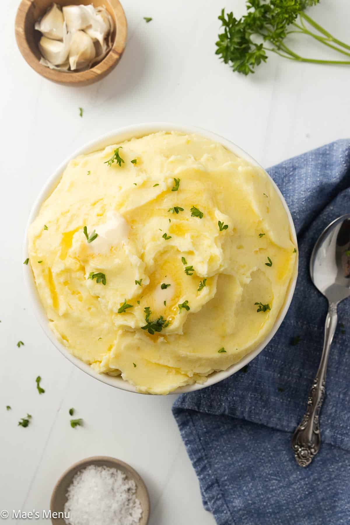 An overhead shot of cream cheese mashed potatoes on the counter with garlic and salt.