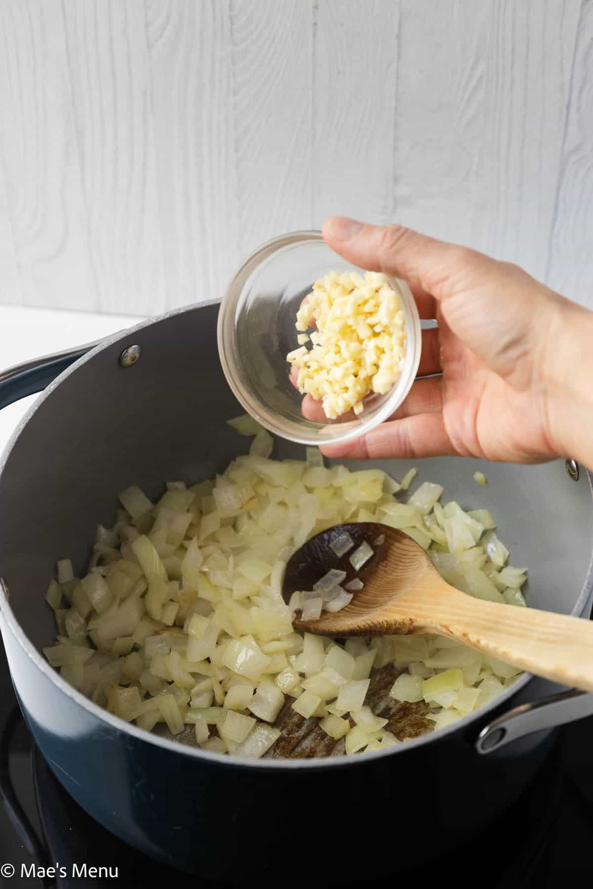 Preparing to add garlic to the pot of sauteeing onions.