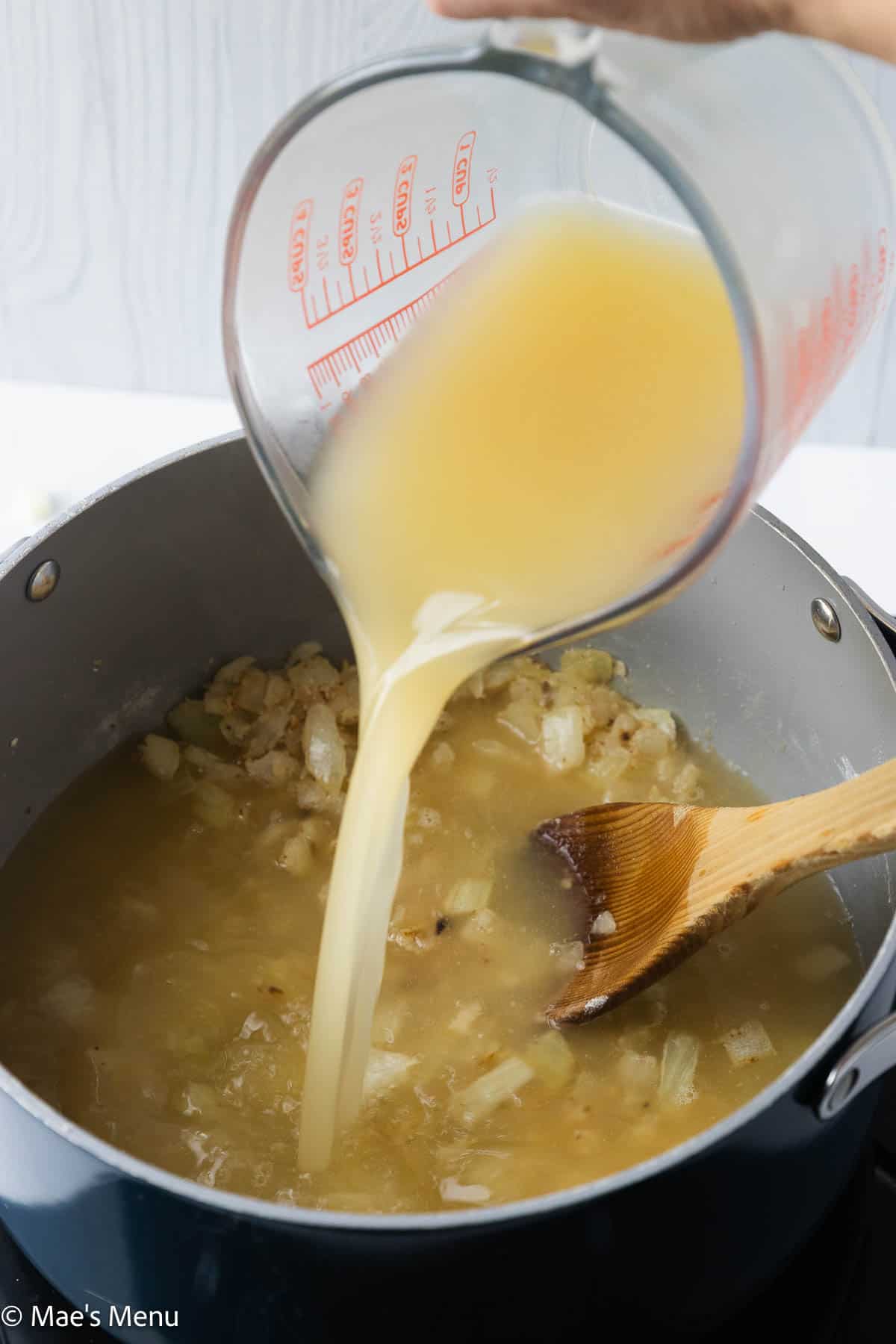 Pouring the broth into the large pot of soup.
