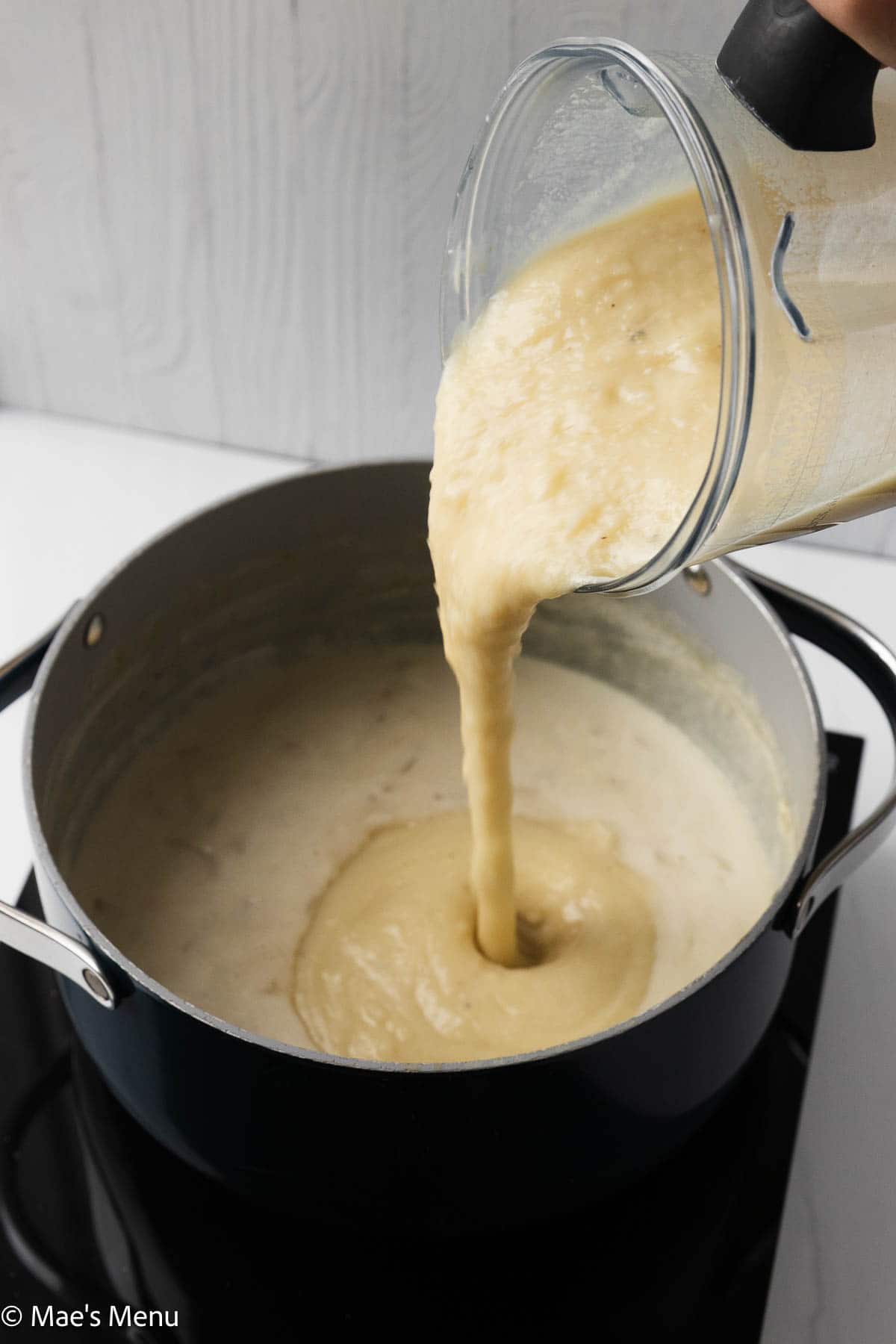 Pouring the blended potato soup into the pot.