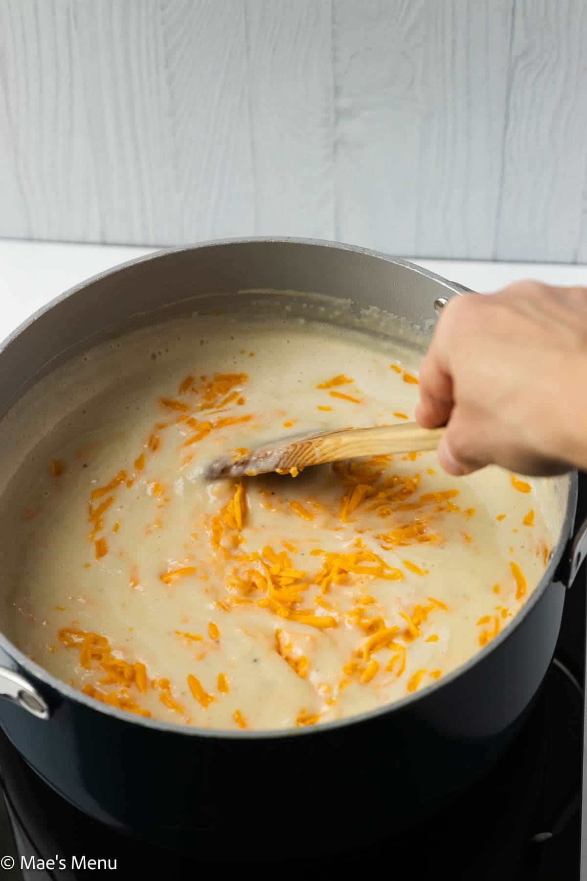 Stirring cheddar cheese into the soup.