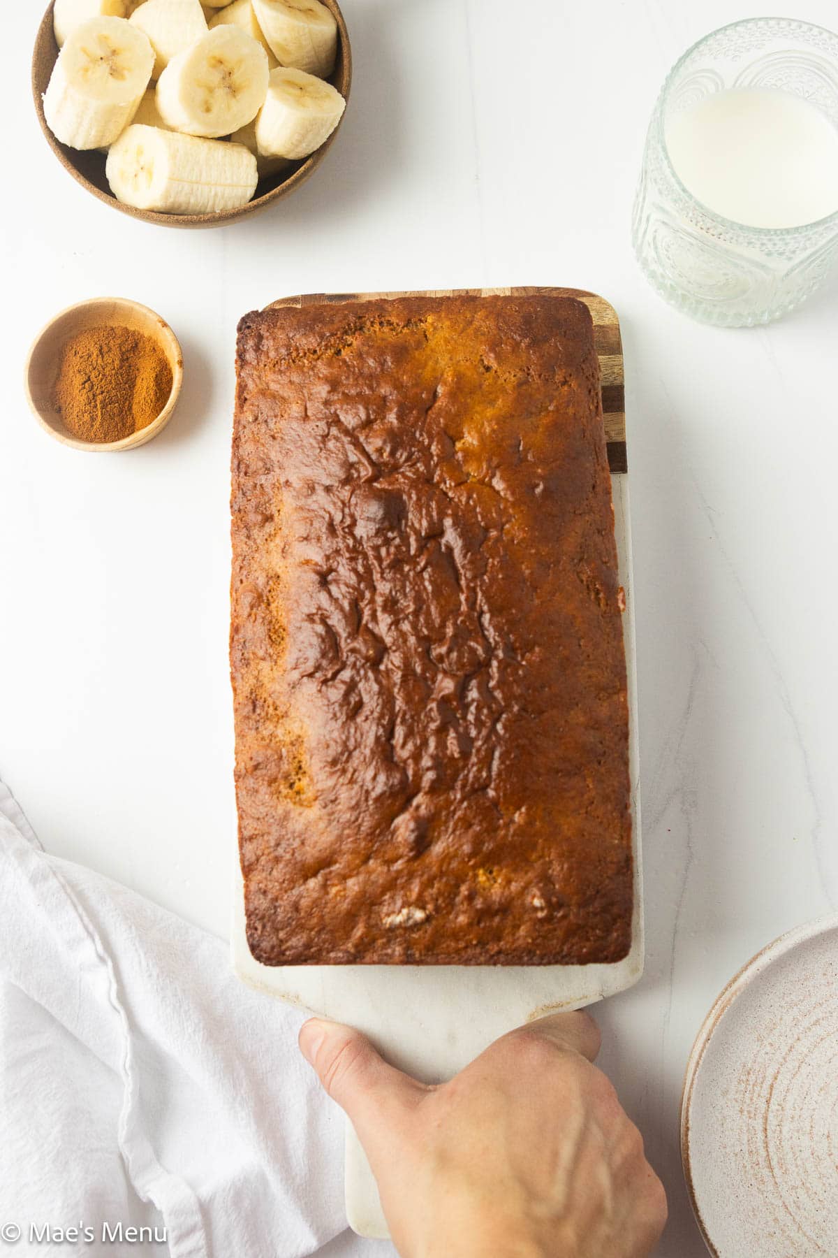 A hand placing out a loaf of high protein banana bread to serve.