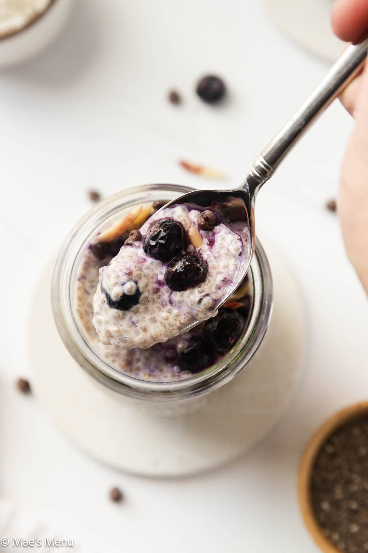 A close-up overhead shot of a spoon scooping the protein chia pudding with blueberries. 