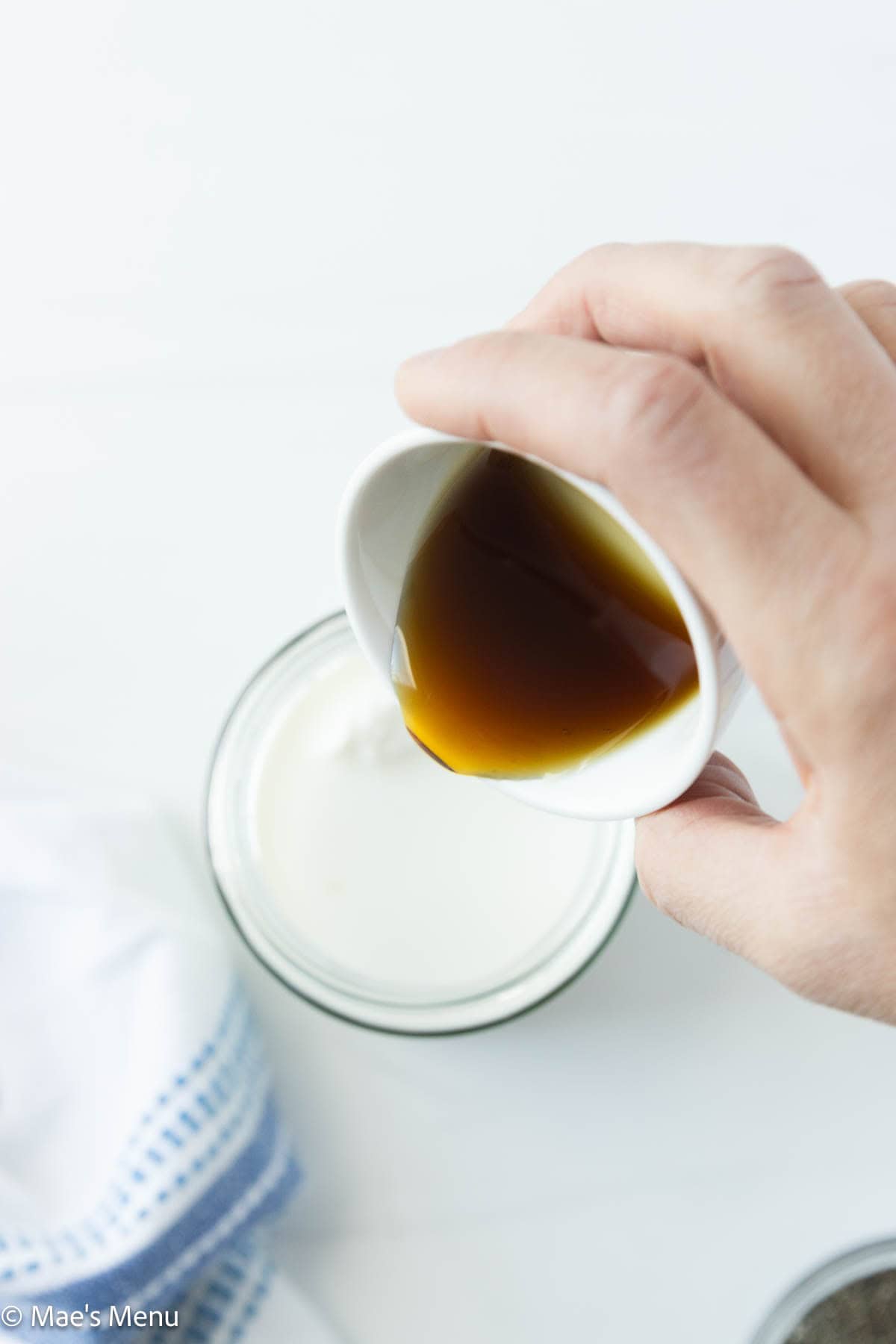 Pouring maple syrup into a jar with milk and yogurt. 