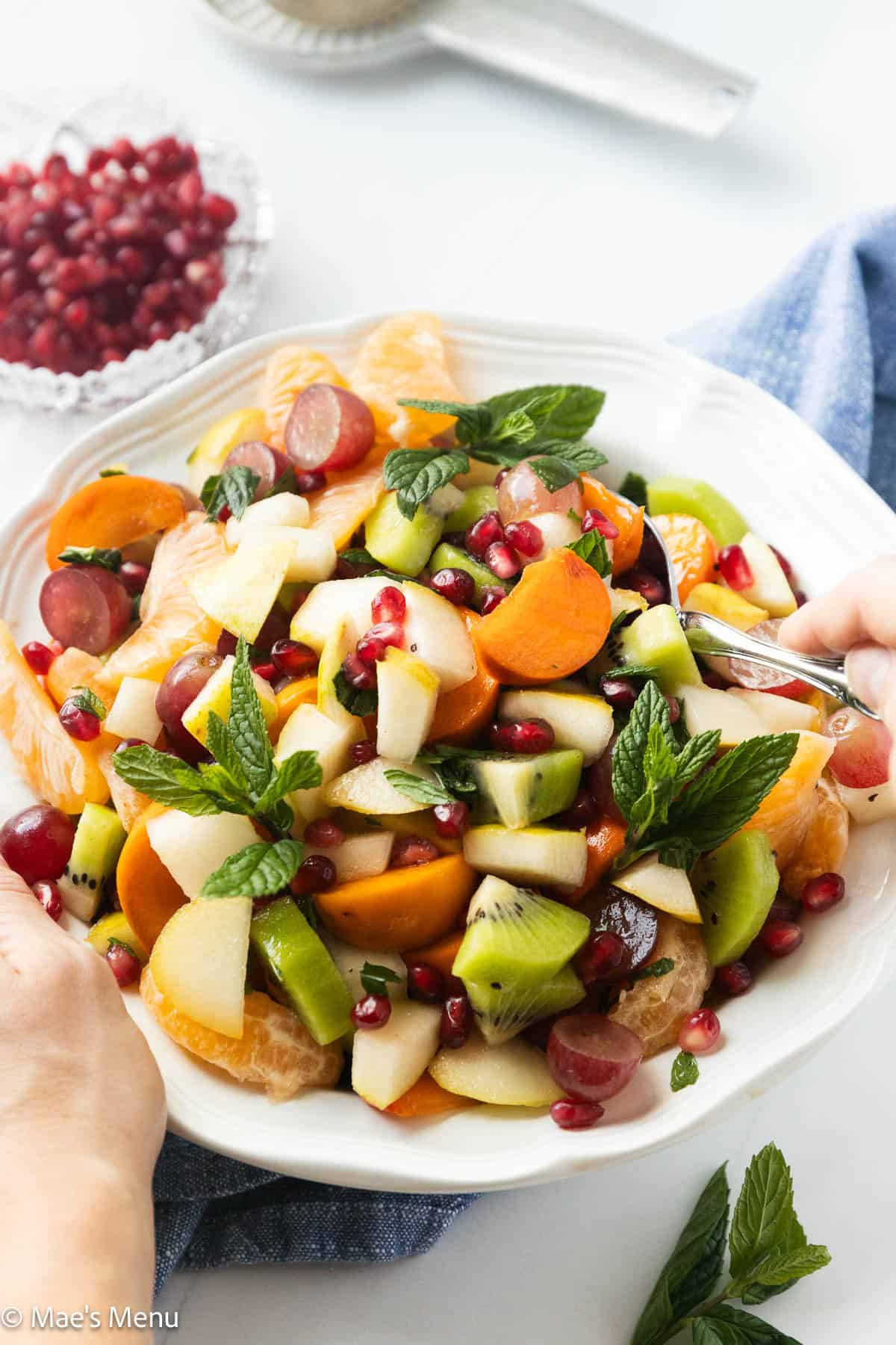 Two hands getting ready to serve winter fruit salad.