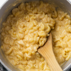 An overhead shot of a pan of 3 cheese mac and cheese with a wooden spoon.