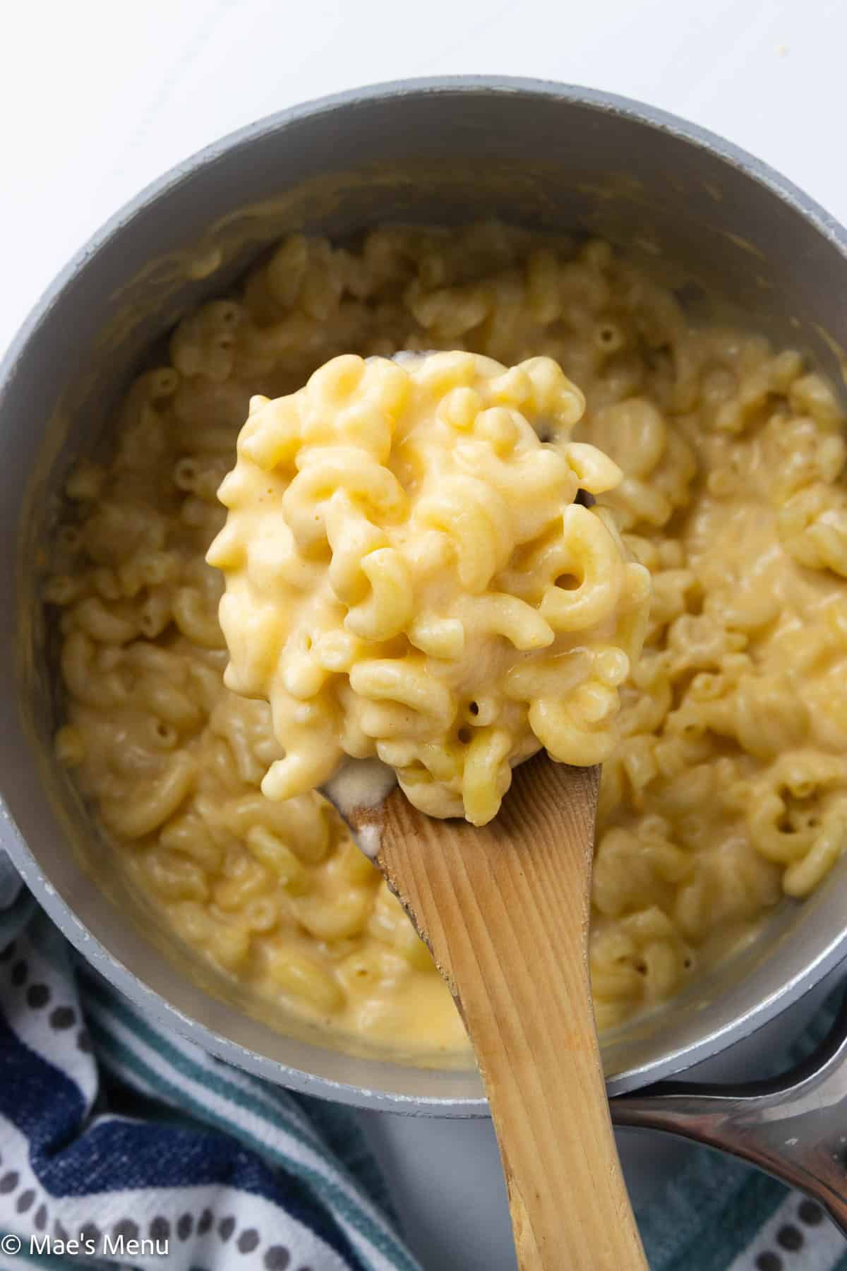 An overhead shot of a scoop of 3 cheese mac and cheese over a saucepan of it.