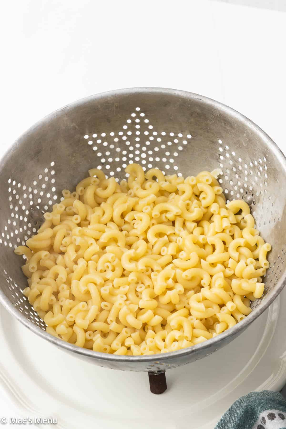 Macaroni draining in a metal colander.